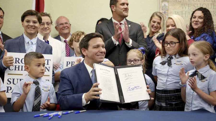 Florida Gov. Ron DeSantis displays the signed Parental Rights in Education, aka the Dont Say Gay bill, flanked by elementary school students during a news conference on Monday, March 28, 2022, at Classical Preparatory school in Shady Hills. (Douglas R. Clifford/Tampa Bay Times via AP)